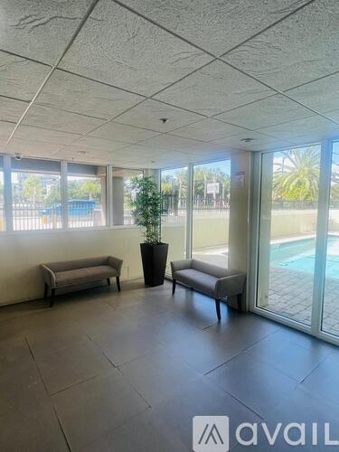 A room with a pool outside the window and two couches.