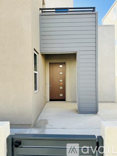 A modern house entrance with a wooden door and a grey wall.