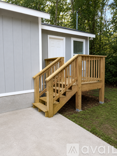 A wooden staircase with a white door and a grey wall.