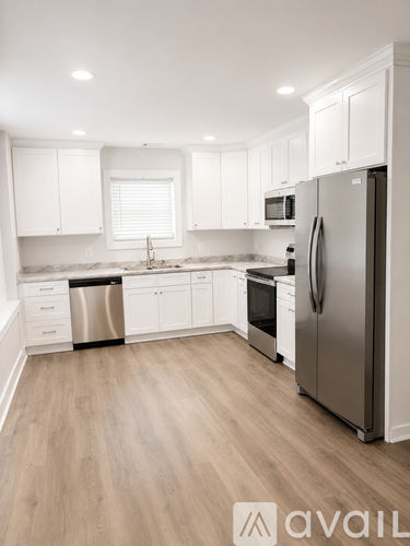 A kitchen with white cabinets and a stainless steel refrigerator.