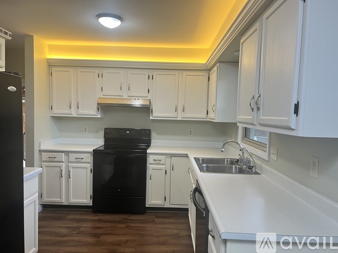 A kitchen with white cabinets and a black fridge.