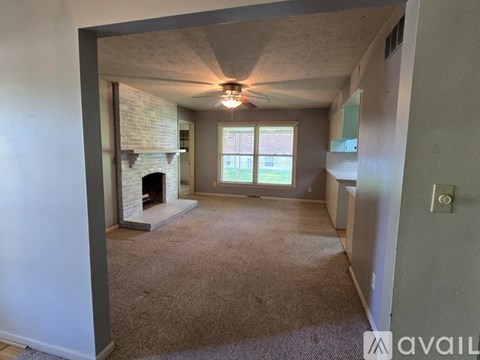A living room with a fireplace and a ceiling fan.