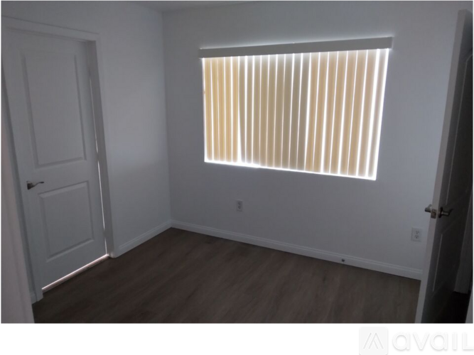 A room with a window covered by horizontal blinds.