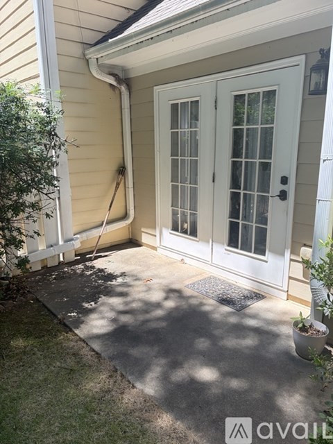 A white door with glass panes is on a house with a grey concrete walkway.