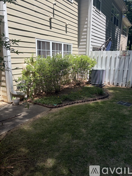 A small garden with a white fence and a green bush.