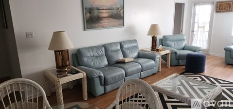 A living room with a grey couch and a painting on the wall.