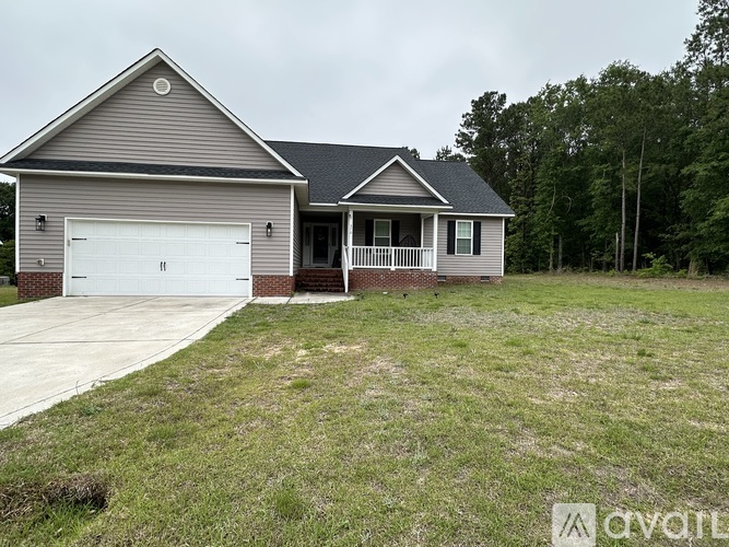 A grey house with a white garage door is situated in a grassy area.