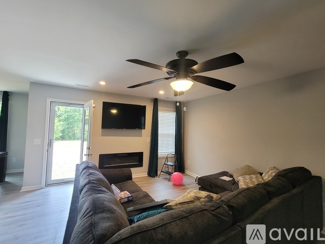 A living room with a grey couch and a ceiling fan.