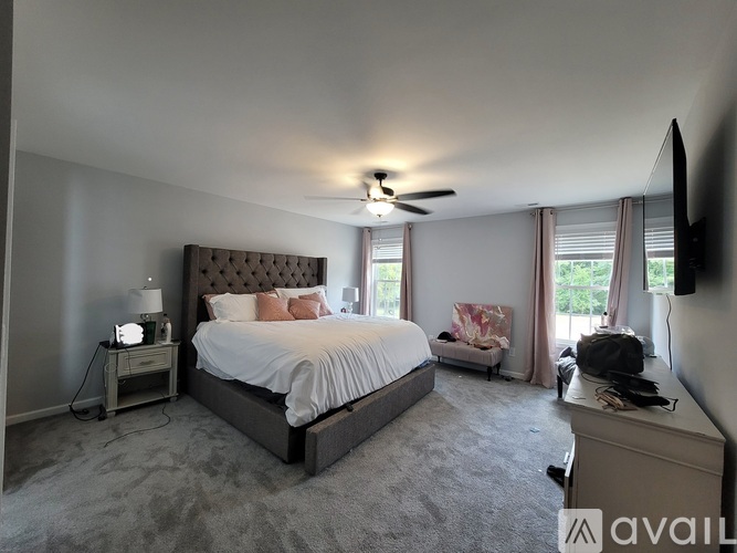 A bedroom with a large bed and a ceiling fan.
