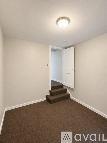 A room with a carpeted floor and a staircase leading to another room.