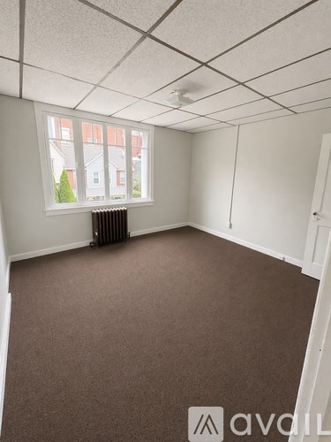 A room with a carpeted floor and a window with a view of a building outside.