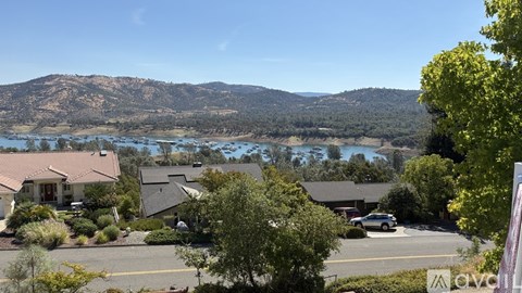 A view of a residential area with houses, trees, and a mountain in the background.