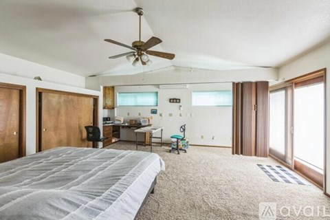 A bedroom with a large bed and a ceiling fan.