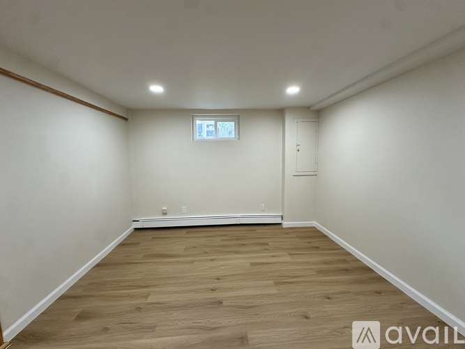 A spacious room with wooden flooring and a window.