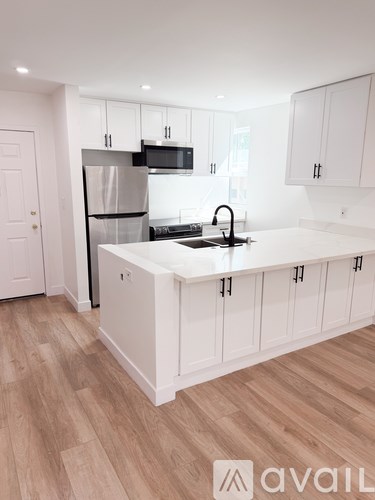 A kitchen with white cabinets and a wooden floor.