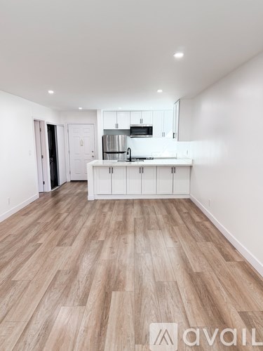 A kitchen with white cabinets and a wooden floor.