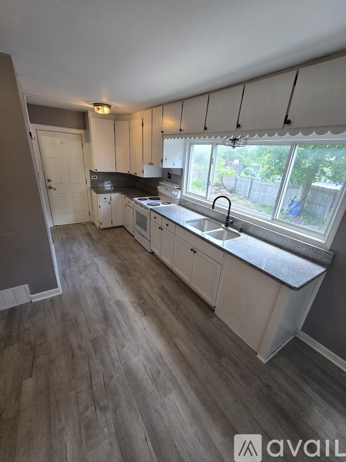 A kitchen with white cabinets and a grey floor.