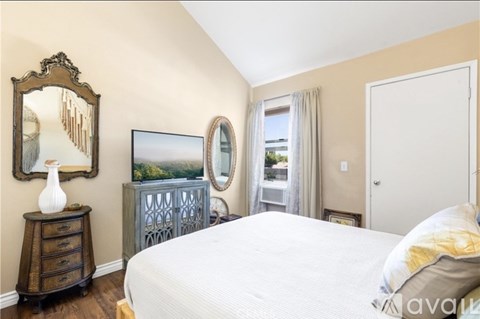 A bedroom with a large bed, a dresser, and a mirror.