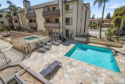 A pool surrounded by a patio with chairs and a table.