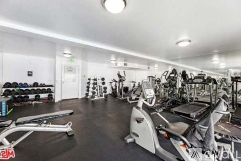 A spacious gym with various exercise equipment and a black floor.