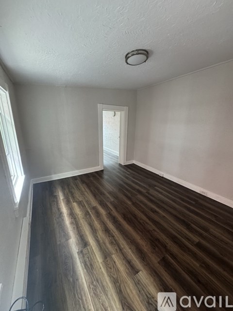 A room with wooden floors and a doorway leading to another room.