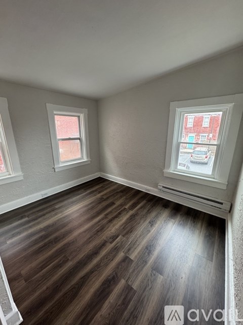 A room with wooden floors and two windows.