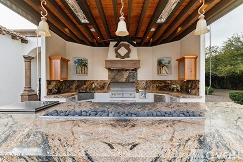 A kitchen with a marble countertop and wooden beams.
