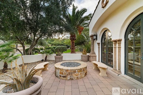 A patio area with a stone fire pit surrounded by potted plants and trees.