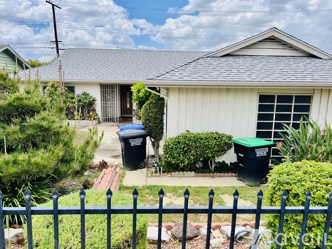 A house with a grey roof and a green bush.