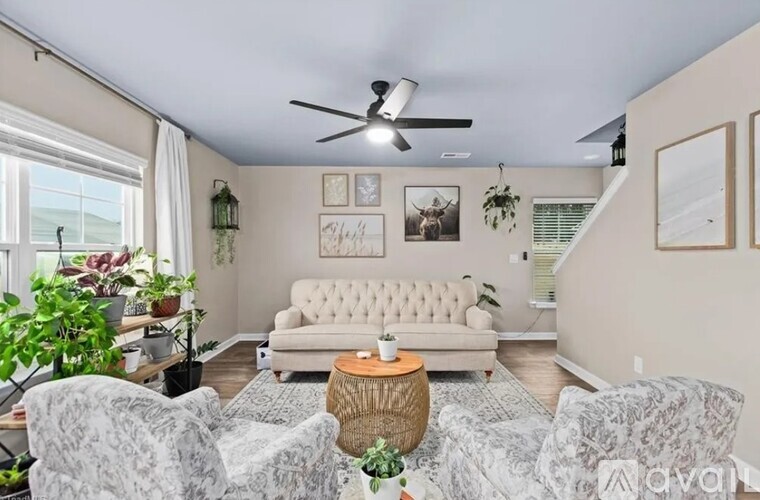 A living room with a white couch, grey chairs, and a ceiling fan.
