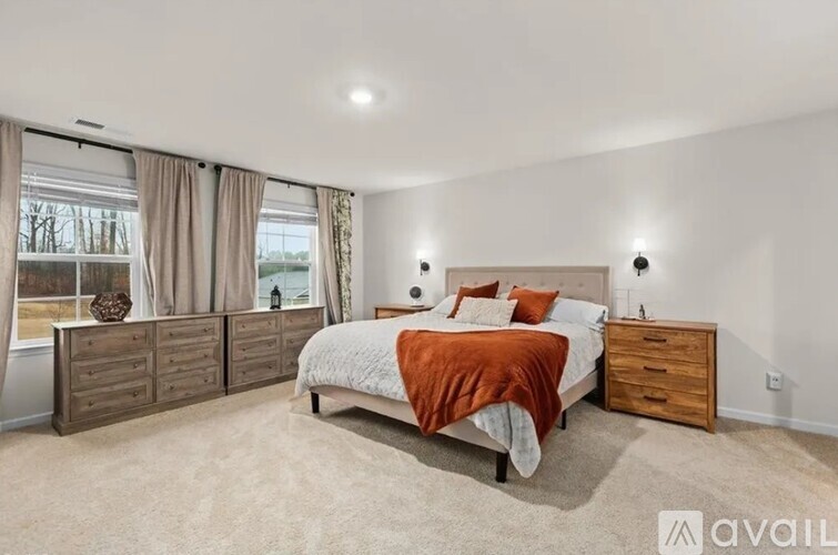 A bedroom with a large bed and a window with curtains.