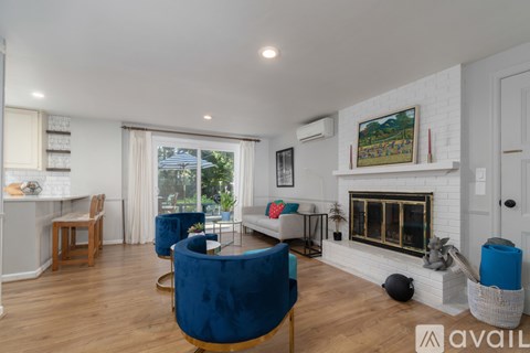 A living room with a blue chair in the foreground and a fireplace in the background.