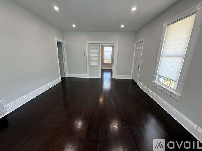A spacious room with wooden floors and white walls.