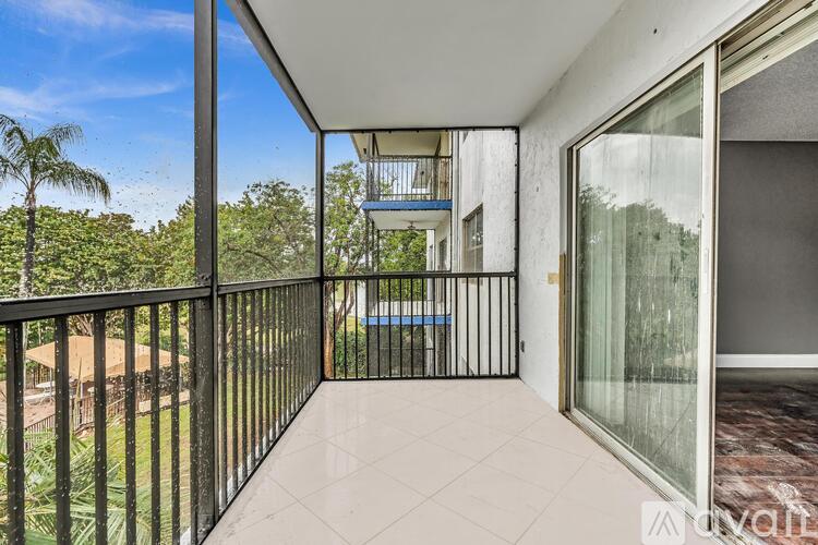 A balcony with a black railing and a view of a pool and trees.