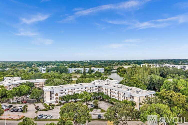 A large white building surrounded by trees and a parking lot.