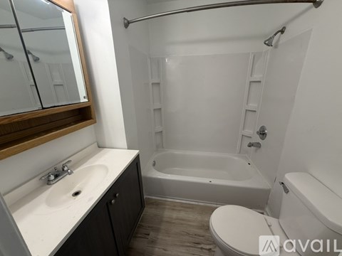 A bathroom with a white tub, sink, and toilet.