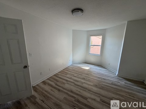 A room with wooden flooring and a window letting in natural light.