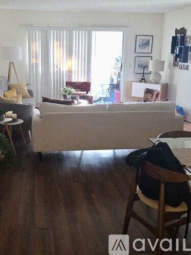 A living room with a couch, chair, and a backpack on the chair.
