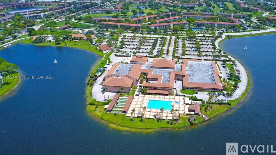 A bird's eye view of a resort with a large building and a pool in the middle of a body of water.