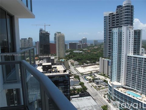 A view from a high-rise building overlooking a cityscape with various buildings and a clear sky.