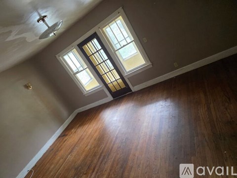 A room with wooden floors and a window with bars on it.