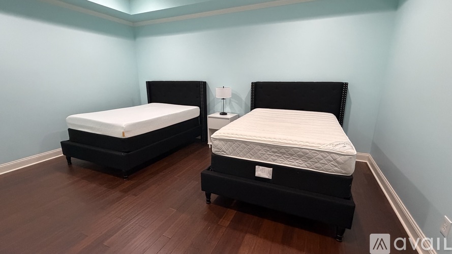Two beds in a room with wooden floors and blue walls.