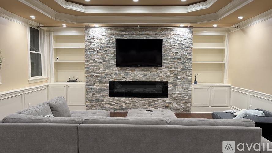 A living room with a grey couch and a stone fireplace.