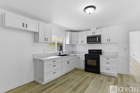 A kitchen with white cabinets and a black stove top oven.