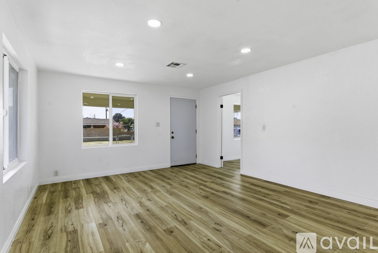 A spacious room with wooden flooring and white walls.