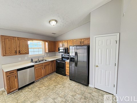 A kitchen with wooden cabinets and a black fridge.