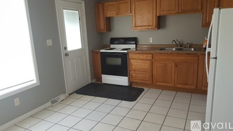A kitchen with wooden cabinets and a black and white tiled floor.