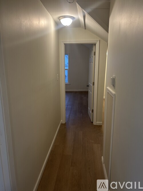 A long hallway with a light on the ceiling and a door at the end.