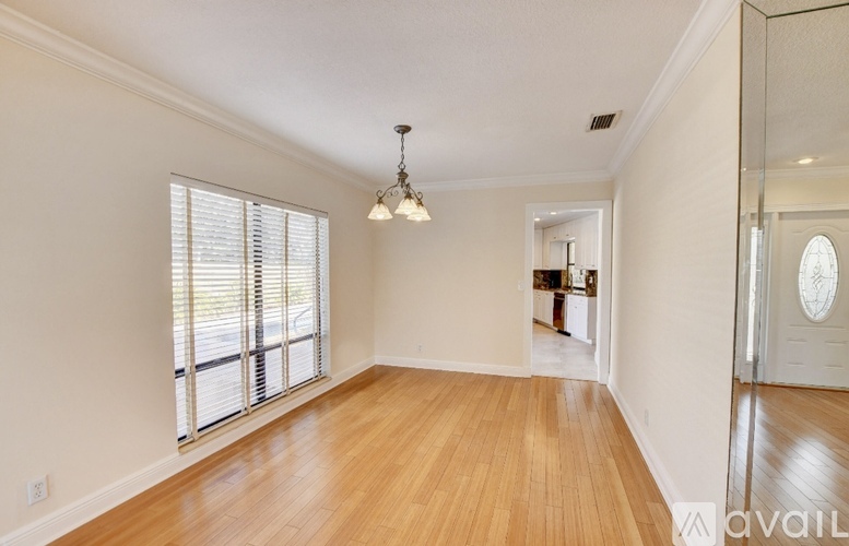 A large empty room with wooden floors and a chandelier.