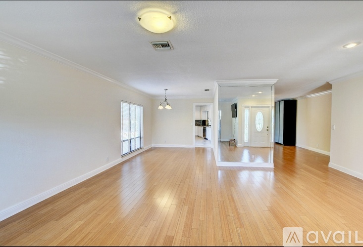 A spacious room with wooden flooring and a large mirror on the wall.